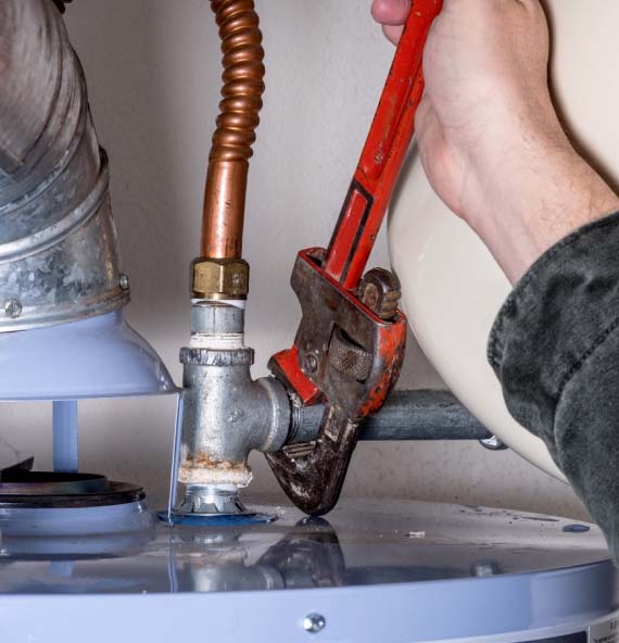 a hand turning a pipe wrench to repair a water heater