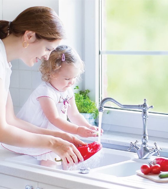 mother and daughter washing vegetables in a sink